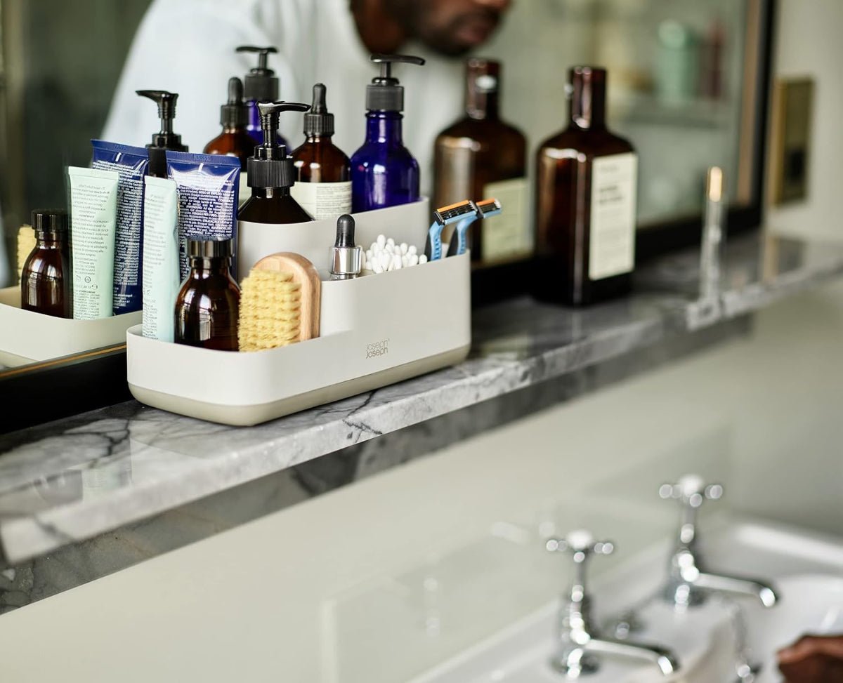 Organized bathroom counter with Joseph Joseph EasyStore Caddy filled with toiletries like toothbrushes, toothpaste, and skincare products